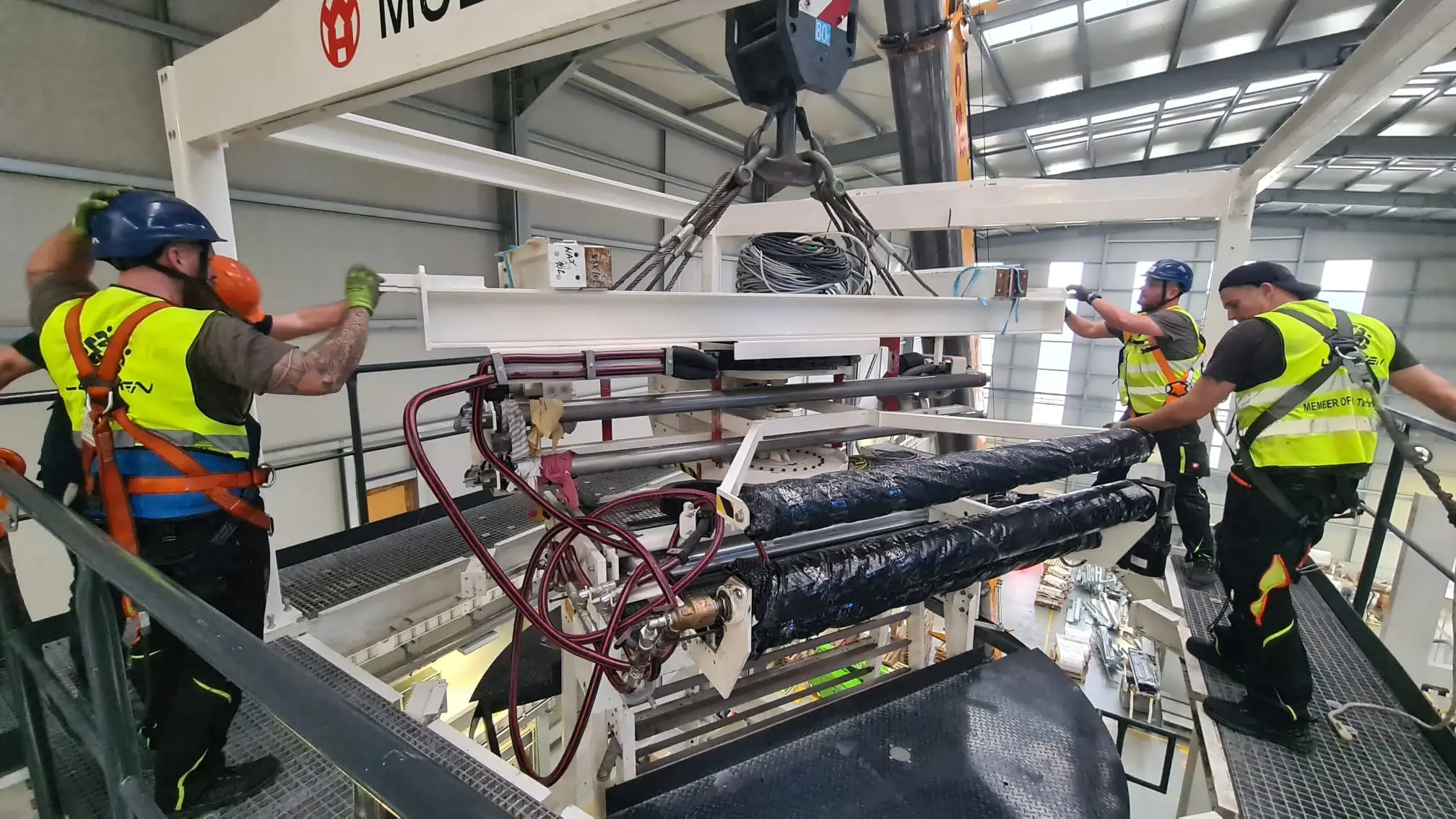 LETKEN team in safety harnesses guiding a suspended machine